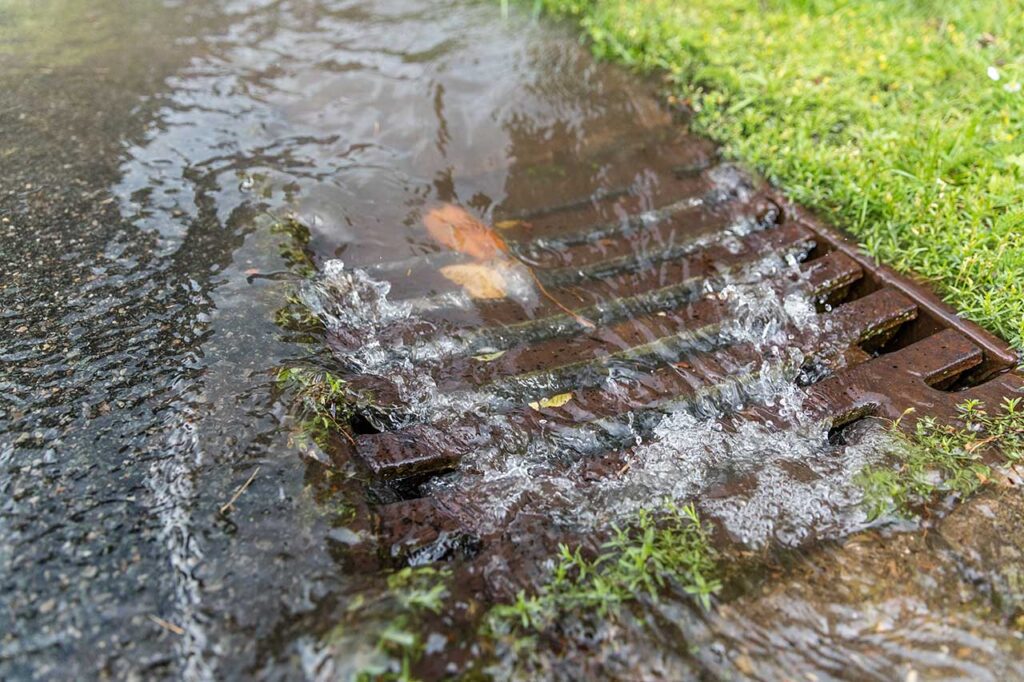 Stormwater going down a drain on the street.